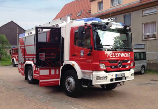 Ein Feuerwehrfahrzeug mit geöffneter Tür im hinteren Bereich.