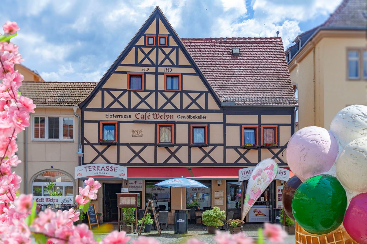 Beiges Fachwerkhaus mit rotem Dach, das Café Welyn in Stadt Wehlen, direkt neben der Touristinformation gelegen.